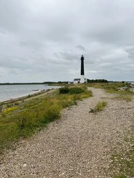 Lighthouse on a Remote Coast Under Dramatic Overcast Sky Stock Photos