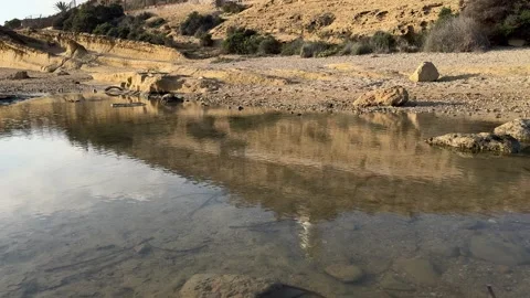 Lighthouse on a rocky hill with calm reflection in clear water below in Alicante Stock Footage 294821346