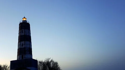 Lighthouse with rotating spotlight during sunset Stock Footage 76825720