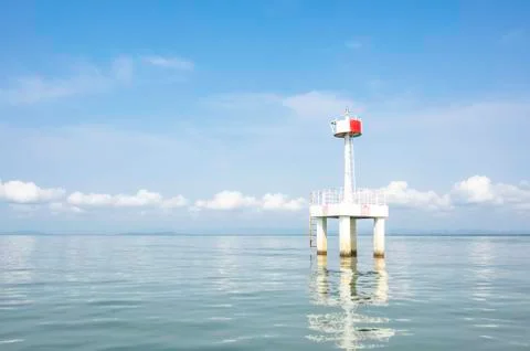 The lighthouse in the sea with eflection of water Background cloud and sky. Stock Photos