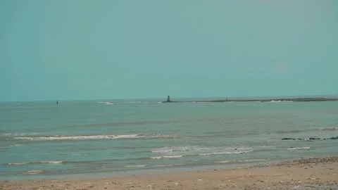 Lighthouse by the sea with gentle waves under clear blue sky 스톡 동영상 332920833