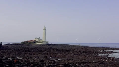 Lighthouse On The Seashore At Low Tide With Distant Wind Turbines In The Evening Stock Footage 281959634