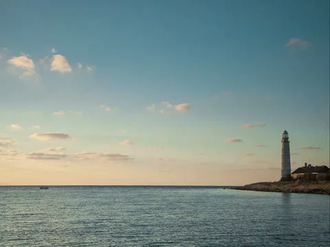 Lighthouse at the seashore under a blue sky with clouds Video stock 70791381