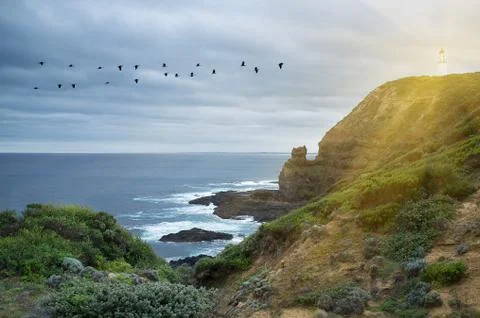 Lighthouse shining protective light over ocean Stock Photos