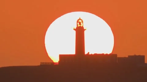 Lighthouse silhouette aligned with sun at sunset minimal orange sky 스톡 동영상 331166730
