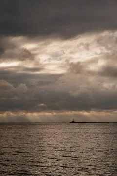 Lighthouse silhouette over sea at dramatic sunset Stock Photos