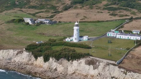 A lighthouse sits on a cliff overlooking a small town Video stock 297950524