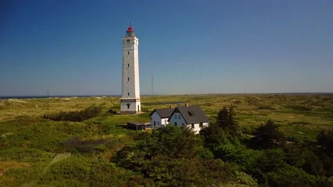 Lighthouse stands tall amidst nature with a clear sky in the background dur.. Stock Footage 339940060