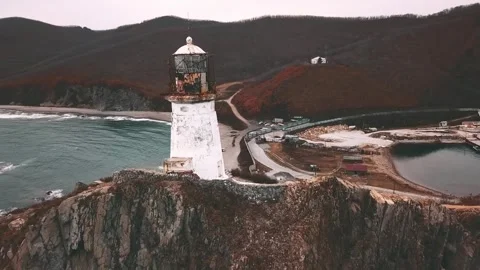 Lighthouse stands tall on cliff by water, overlooking picturesque landscape Stock Footage 274828451