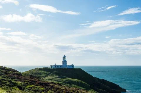 The lighthouse at Strumble Head, surrounded by the wild coastline and sea Stock Photos