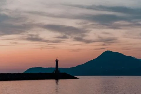 Lighthouse at sunset. Against the backdrop of the mountains. Stock Photos