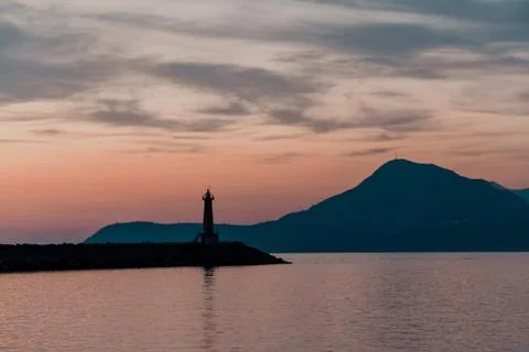 Lighthouse at sunset. Against the backdrop of the mountains. Stock Photos