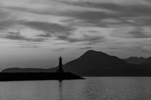 Lighthouse at sunset. Against the backdrop of the mountains. Stock Photos