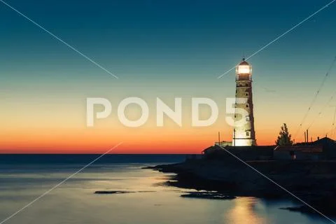Lighthouse at sunset in the twilight in clear weather Stock Photos