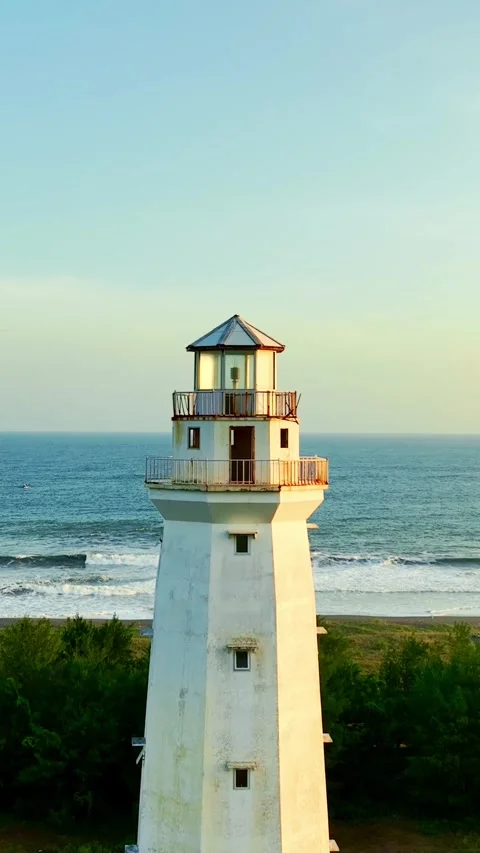 Lighthouse tower centered against beach and ocean Stock Footage 335432662