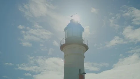 Lighthouse tower in the day with sun flaring behind the top Stock Footage 106436346