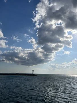 Lighthouse Under Dramatic Sunlit Clouds Over the Sea Stock Photos