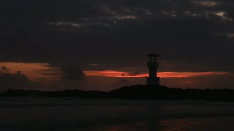 Lighthouse  with waves washing sandy beach at sunset. Stock Footage 68430742
