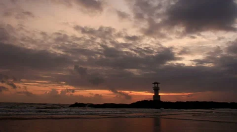 Lighthouse  with waves washing sandy beach at sunset. Stock Footage 68431023