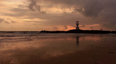 Lighthouse  with waves washing sandy beach at sunset. Stock Footage 68452960
