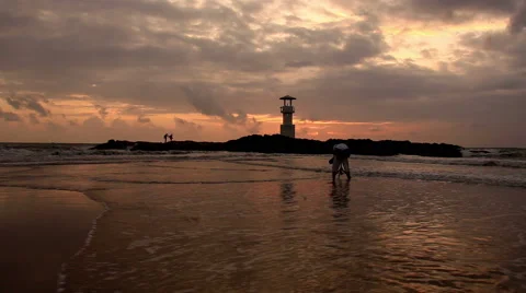 Lighthouse  with waves washing sandy beach at sunset. Stock Footage 68452964