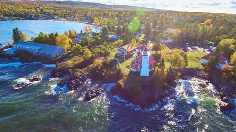Lighthouse with white waves a sun flare and an aerial shot of the lake with fall 스톡 사진