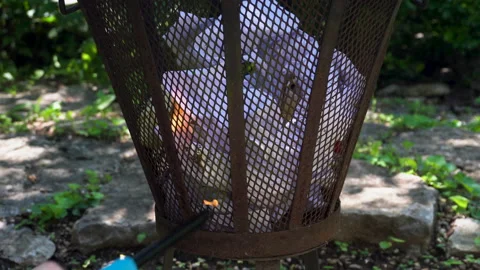 Lighting and Burning Paper Trash in Metal Fire Cage Stock Footage 147627246