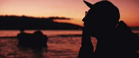 Lighting and smoking a cigarette at sunset by the sea Video stock 324463328