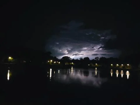 Lighting between the cumulonimbus clouds reflection on a lake Stock Photos