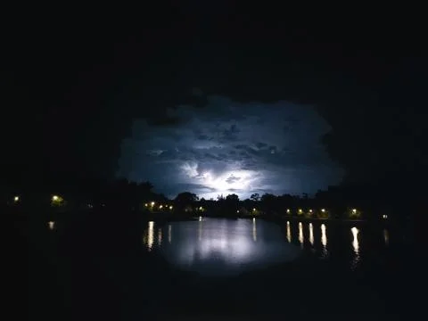 Lighting between the cumulonimbus clouds reflection on a lake Stock Photos