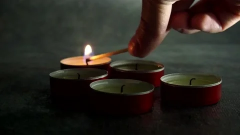 Lighting candles in the dark. Small round holiday candles. Soothing atmosphere. Stock Footage 168650974