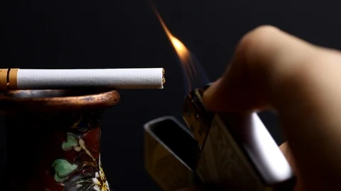 Lighting a cigarette placed on a small cloisonne vase Stock Footage 108581060
