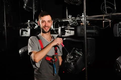The lighting engineer repairs the light device on stage. Stock Photos