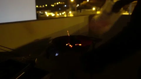 Lighting the fire of a grill and blowing air with the sparks of the coal at Stock-Footage 155793059