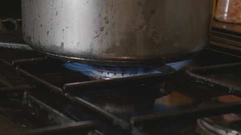 Lighting a flame on a hob stove under a metal saucepan Stock Footage 119185509