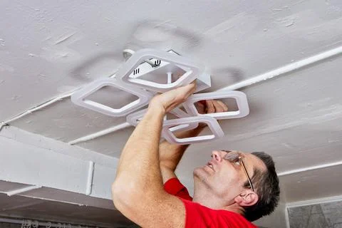 Lighting installation work includes electrician fitting LED chandelier to c.. Stock Photos