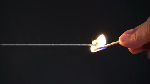 Lighting a sparkler with a lit match - Horizontal pparkler on black background Stock Footage 141220525
