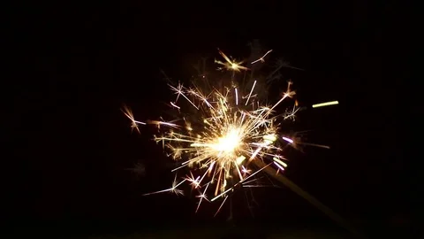Lighting up a sparkler using a lighter in night. Close Up Stock Footage