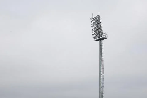 The lighting tower of the stadium on the background of the sky and clouds Stock Photos