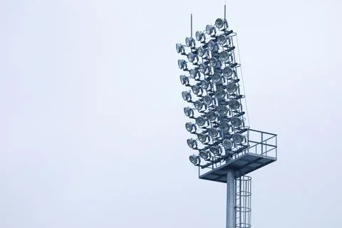 The lighting tower of the stadium on the background of the sky and clouds Stock Photos