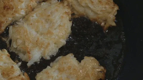 Lightly fried hash browns are fried in a pan in oil the camera moves Stock Footage 108008404