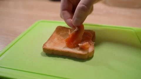 Lightly salted trout is placed on white bread toast close-up on a green kitchen Stock Footage 322170595