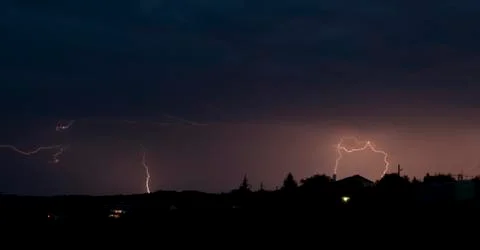 Lightning bolt striking in the sky from clouds Stock Photos