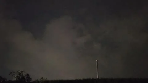 Lightning clouds illuminate silhouetted garden hedge with flashing atmosphere Stock Footage 343876959