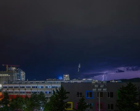 Lightning dances in the dark night sky above a vibrant cityscape during a s.. Fotos Stock