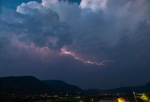 Lightning discharge with side branches high in the sky above the mountains Stock Photos