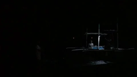 Lightning flashes in the horizon while fishermen are tending to fish nets Stock Footage 289465112
