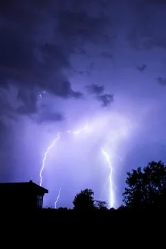Lightning flashes over the night sky during thunderstorm. Stock Photos