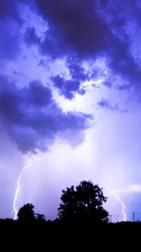 Lightning flashes over the night sky during thunderstorm. Stock Photos