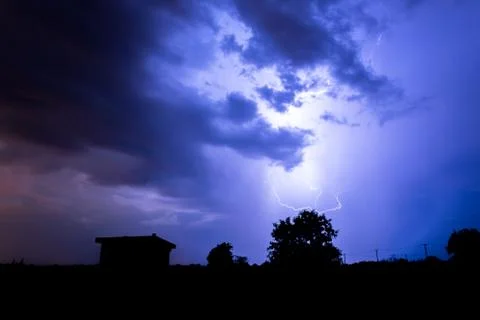 Lightning flashes over the night sky during thunderstorm. Stock Photos